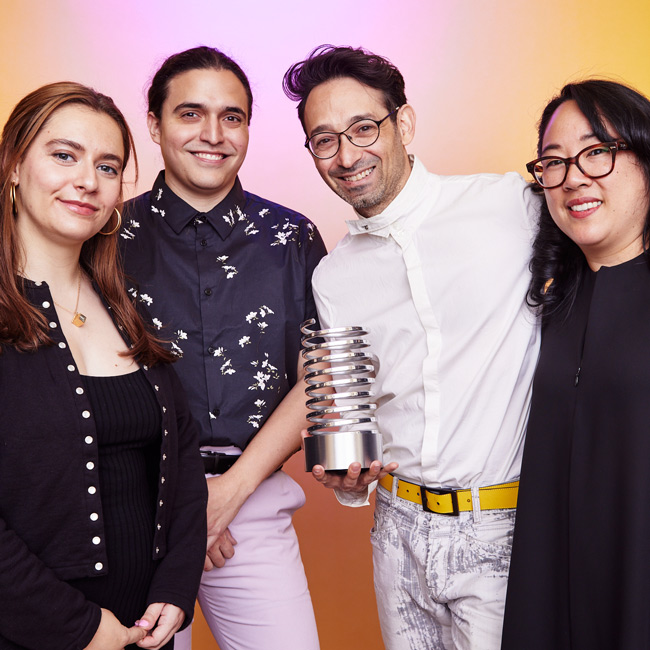 Four people holding an award against a pink/yellow background