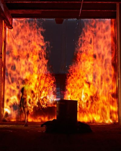 Night time photograph of a tunnel onto which is projected a faux 3D perspective of a firescape stretching backwards in a narrow column into infinity