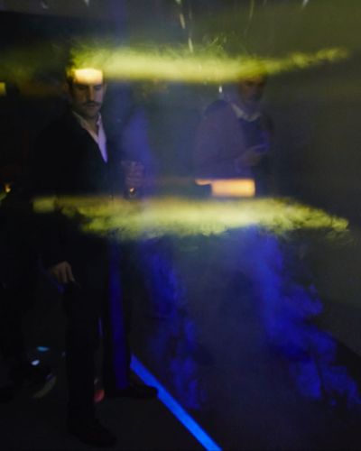 Close-up photograph of a projector encased in a triangular, DIY shell-like structure that comes to a point about six inches in front of the projector lens, only allowing a narrow beam of red light to escape into the room.