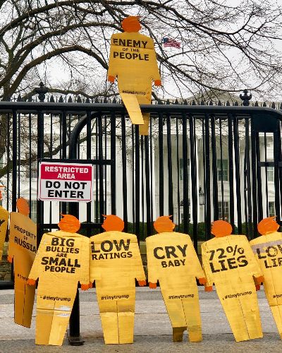 12 golden tiny trumps standing on their own accord against a gate outside of the White House