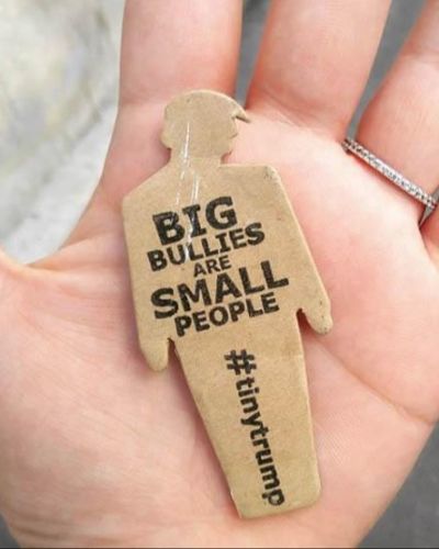 a photograph of a tiny trump in the palm of someone's hand