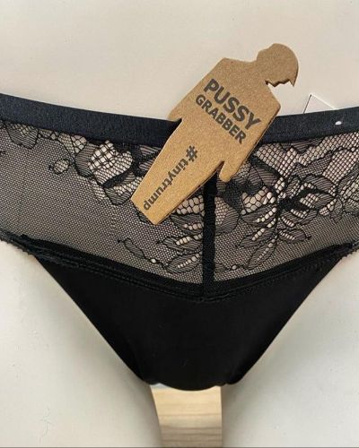 a photograph of a tiny trump with the slogan 'Pussy Grabber' stuck to a pair of panties being shown on a mannequin