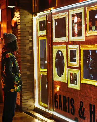 Photograph showing a 3/4 view of a video installation as one would see it from the street, 20 feet or so from its center. Also in the frame is a viewer looking at the video installation with a long view of the rest of the block behind her.