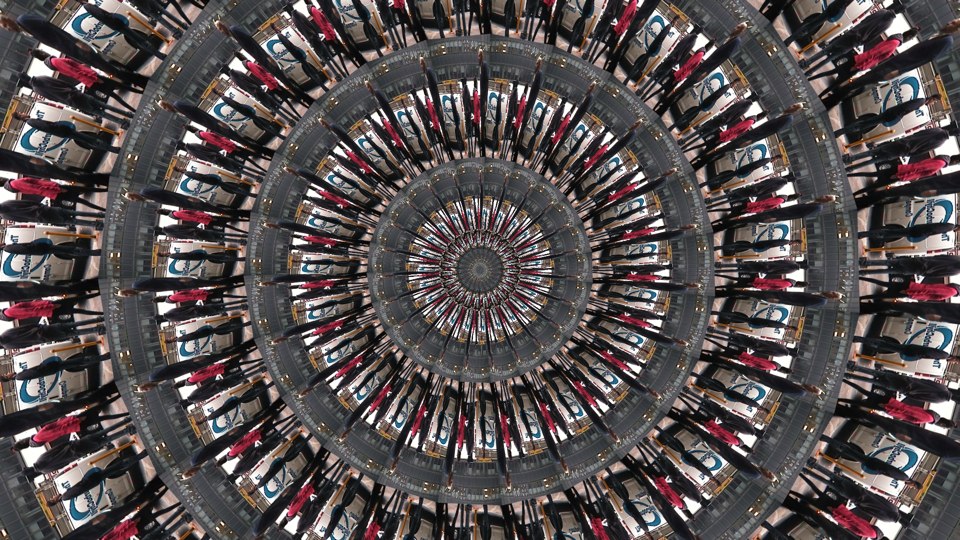 Algorithmically generated kaleidoscopic image consisting of a series of infinite-mirror-esque concentric discs, each one subdivided into multiple tranches that show the same image, albeit rotated by a consistent amount across the disc. In this case, the image that gets repeated across all discs at different angles is a photograph of a woman in a red jacket walking down the sidewalk flanked by two taller people in black jackets.