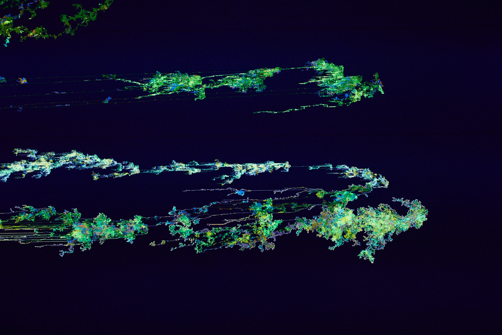 Close-up photograph of the image above which shows three striated and somewhat squid-like green, white, and purple striated, organically shaped pixelated forms against a deep blue background.