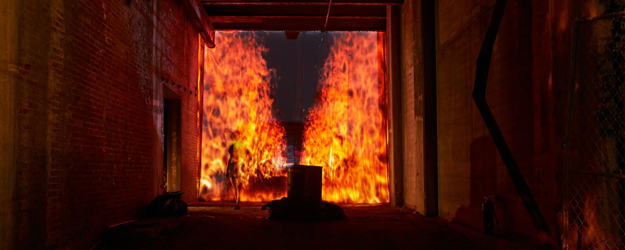 Nightime photograph of a tunnel onto which is projected a faux 3D perspective of an firescape streching backwards in a narrow column into infinity