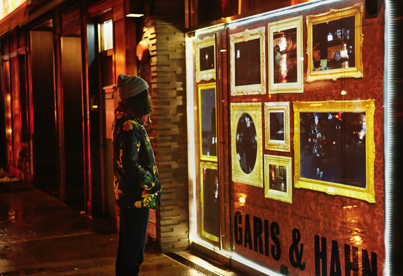 Photograph showing a 3/4 view of a video installation as one would see it from the street, 20 feet or so from its center. Also in the frame is a viewer looking at the video installation with a long view of the rest of the block behind her.