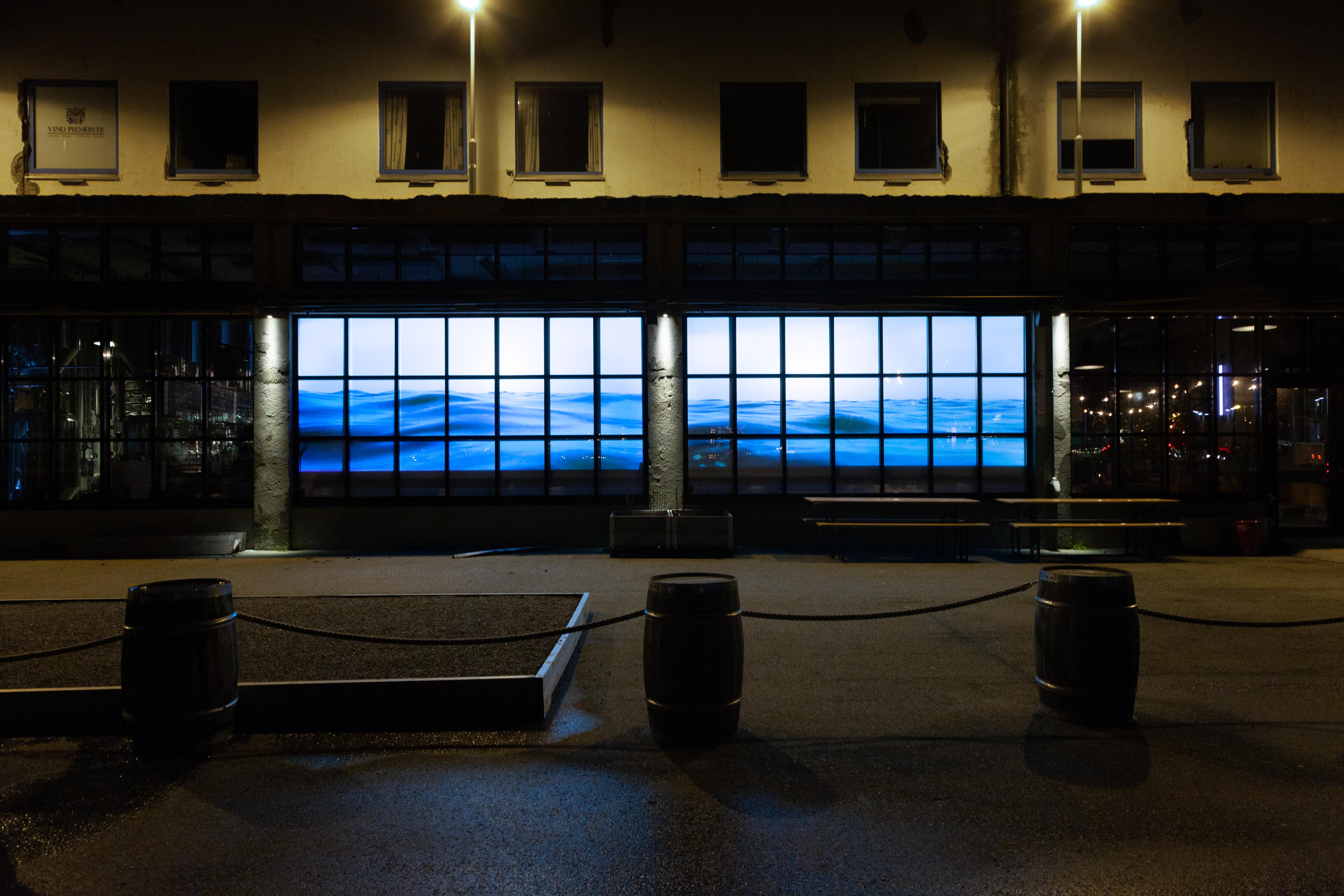Tight shot of Water Will Be Here projected into the windows of Molo Brew